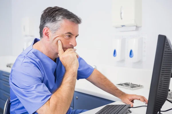 Dentista sério sentado e usando computador — Fotografia de Stock