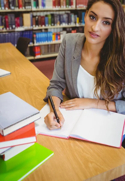Smiling brunette student doing her assignment — Stock Photo, Image