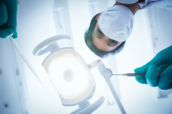 Dentista feminina em máscara cirúrgica segurando ferramentas dentárias — Fotografia de Stock