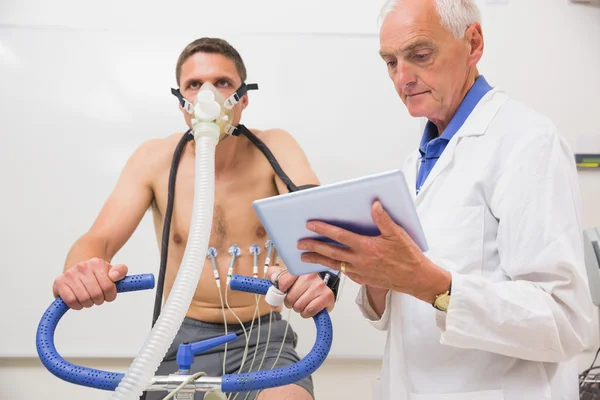 Doctor showing tablet pc to man doing fitness test — Stock Photo, Image