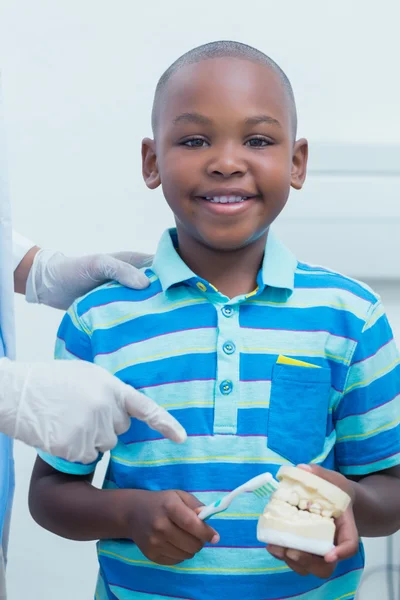 Дантист учит мальчика чистить зубы — стоковое фото