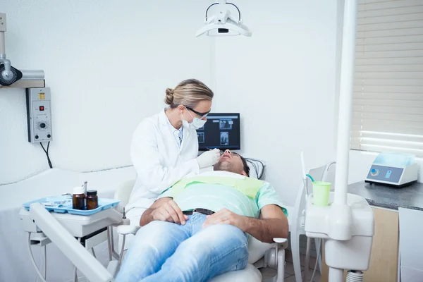 Dentista femminile esaminando denti mans — Foto Stock