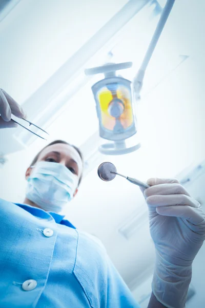 Dentista femenina en máscara quirúrgica sosteniendo herramientas dentales — Foto de Stock