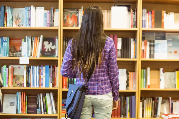 Universiteitsstudent permanent in de boekenkast — Stockfoto