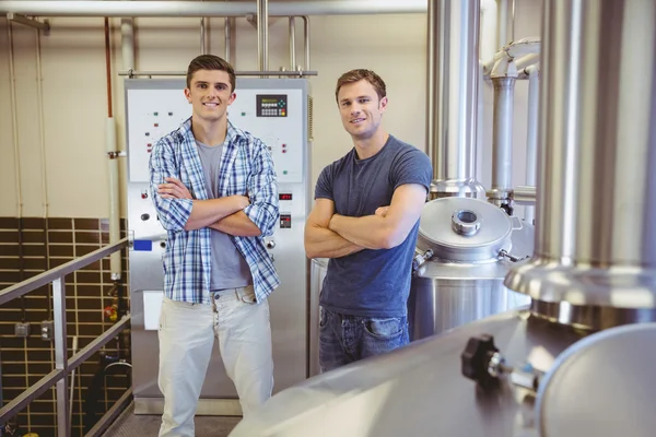 Jonge mannen met gekruiste armen glimlachen op camera — Stockfoto