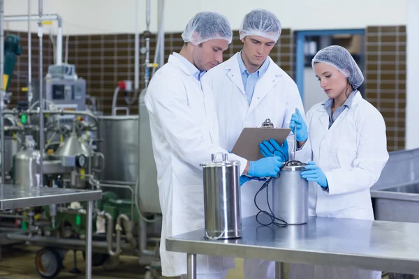 Man schrijven op Klembord terwijl collega's product testen — Stockfoto