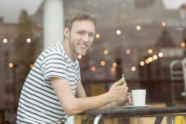 Estudante sorrindo sentado com uma bebida quente — Fotografia de Stock