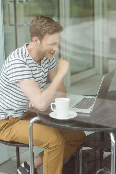 Estudante sorrindo usando laptop no café — Fotografia de Stock