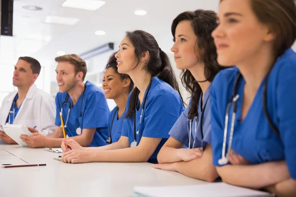 Estudiantes de medicina escuchando sentados en el escritorio — Foto de Stock