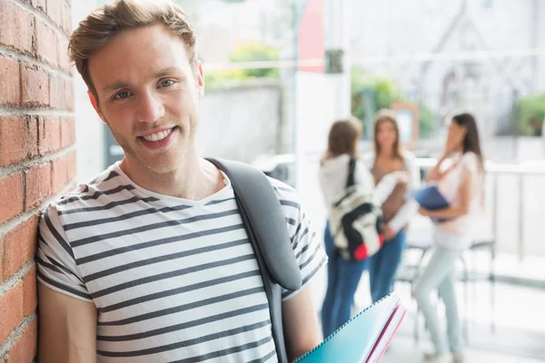 Guapo estudiante sonriendo y sosteniendo bloc de notas —  Fotos de Stock