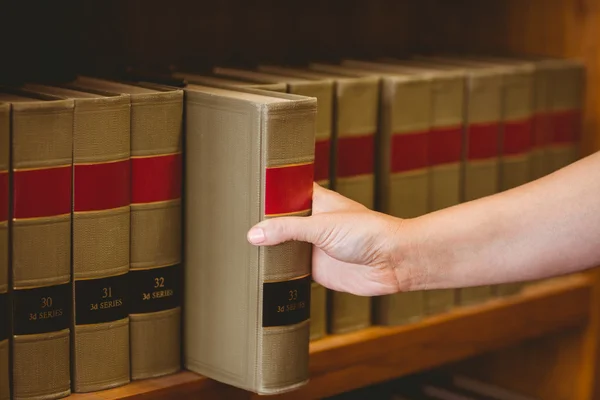 Hand nimmt ein Buch aus dem Bücherregal — Stockfoto