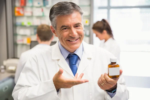 Senior pharmacist showing medicine jar — Stock Photo, Image