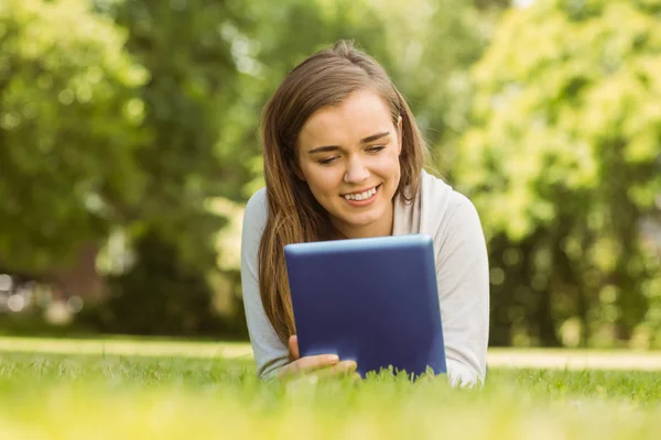 Smiling university student lying and using tablet pc — Stock Photo, Image