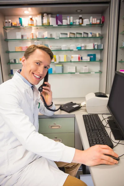 Farmacêutico feliz no telefone usando computador — Fotografia de Stock