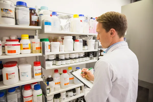 Handsome pharmacist writing on clipboard — Stock Photo, Image