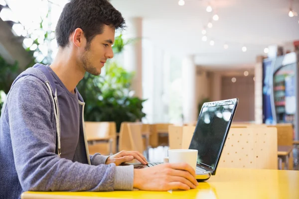 Ung student med sin laptop i café — Stockfoto