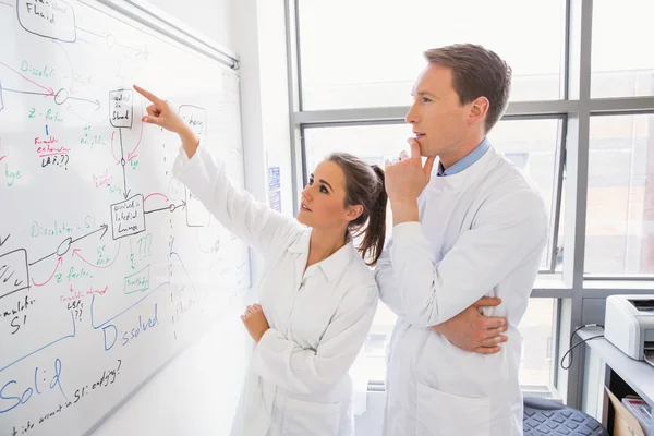 Science student and lecturer looking at whiteboard — Stock Photo, Image