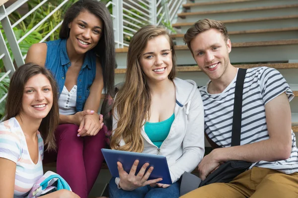 Estudiantes sonrientes sentados en escalones con tablet pc —  Fotos de Stock