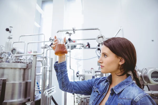 Stijlvolle brunette in denim jasje kijken naar bekerglas van bier — Stockfoto