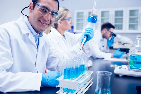 Estudiante de ciencias usando pipeta en el laboratorio para llenar tubos de ensayo — Foto de Stock