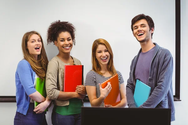 Студенты, стоящие и улыбающиеся перед камерой с блокнотами — стоковое фото