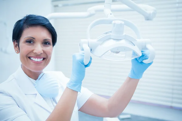 Sonriente dentista hembra ajustando la luz —  Fotos de Stock