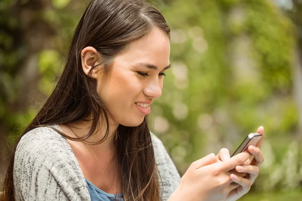 Lächelnde Studentin per SMS auf ihrem Handy — Stockfoto