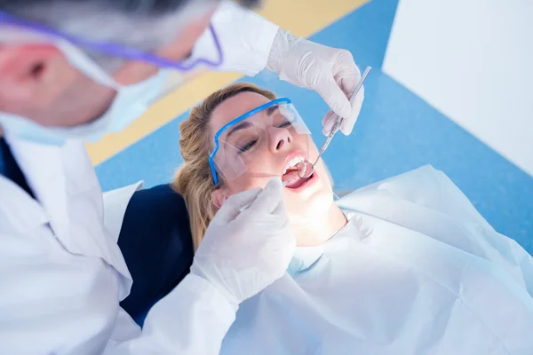 Dentista examinando los dientes de un paciente — Foto de Stock