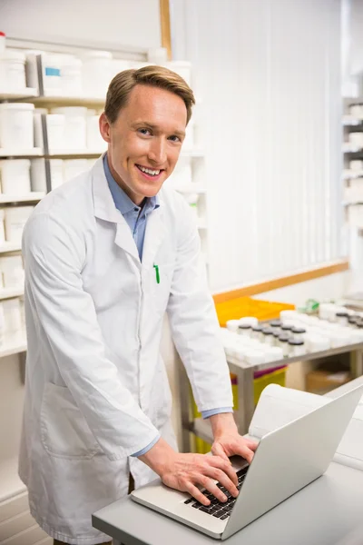 Happy pharmacist using his laptop — Stock Photo, Image