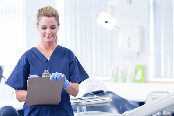 Smiling dentist writing in clipboard Royalty Free Stock Photos