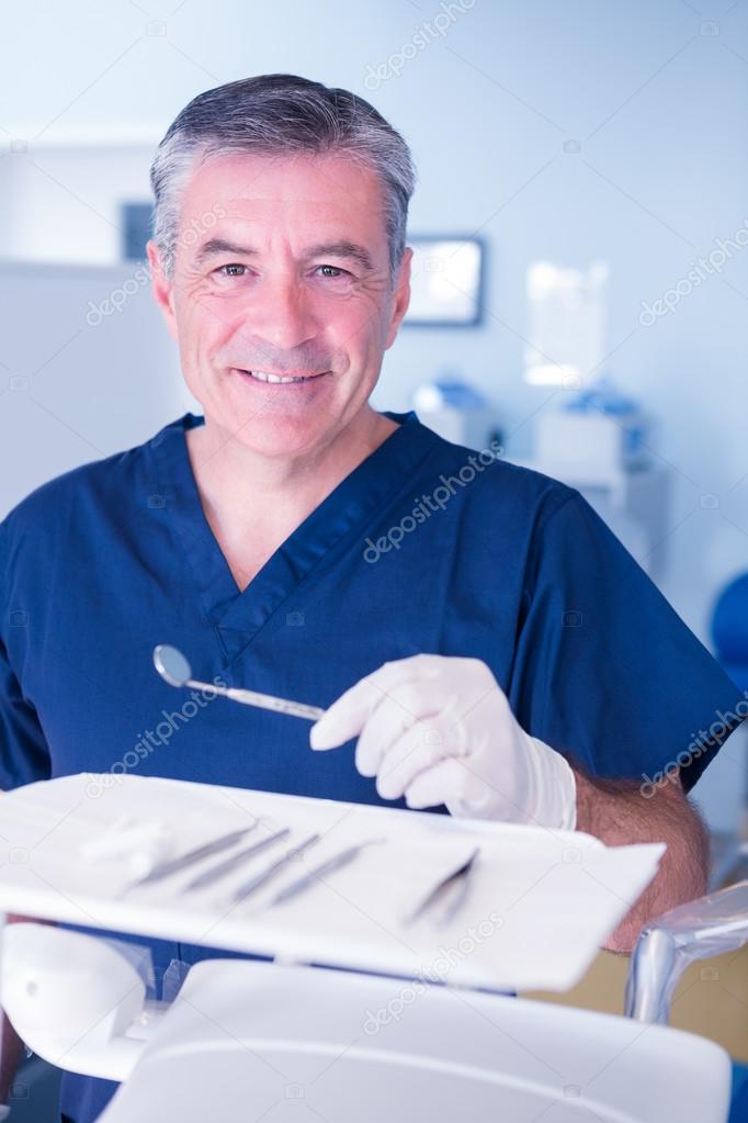 Dentist in blue scrubs holding tools — Stock Photo © Wavebreakmedia