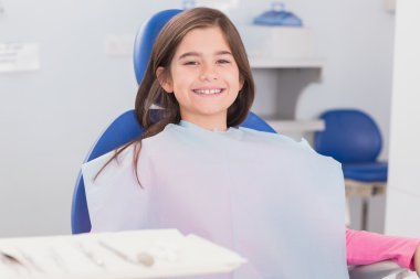 Smiling young patient sitting in dentists chair clipart
