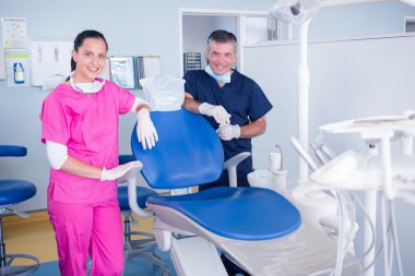 Dentist and assistant inviting you to the chair clipart