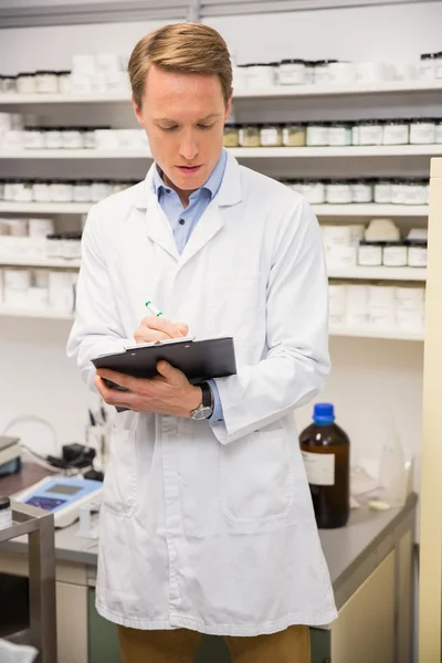 Handsome pharmacist writing on clipboard — Stock Photo, Image