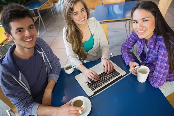 Jóvenes estudiantes haciendo la tarea en el ordenador portátil juntos — Foto de Stock