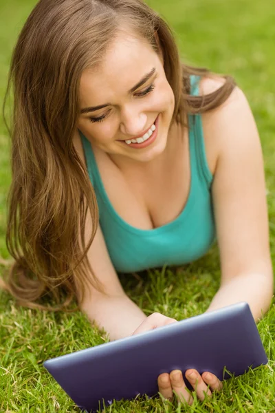 Smiling university student lying and using tablet pc — Stock Photo, Image