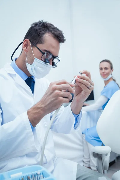 Dentista concentrado mirando la herramienta dental — Foto de Stock