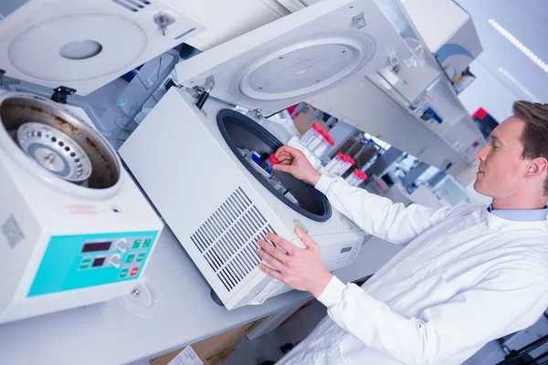 Chemist in lab coat using a centrifuge — Stock Photo, Image