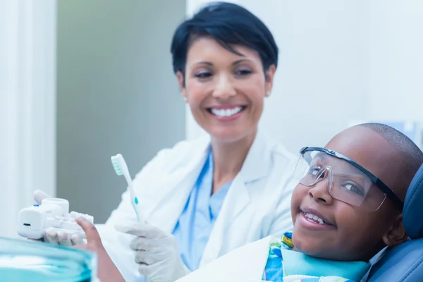 Dentist teaching boy how to brush teeth — Stock Photo, Image