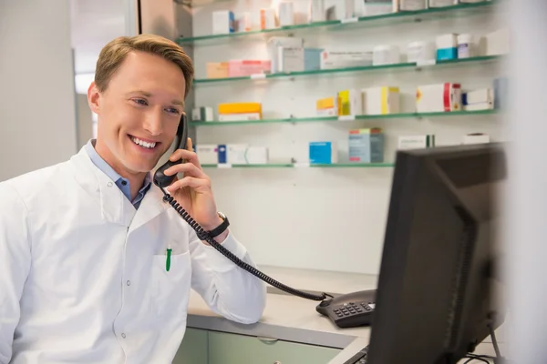 Gledelig farmasøyt på telefonen med datamaskin – stockfoto