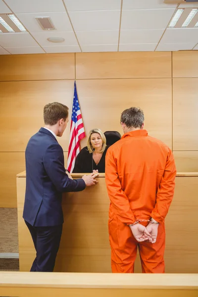 Lawyer and judge speaking next to the criminal in jumpsuit — Stock Photo, Image