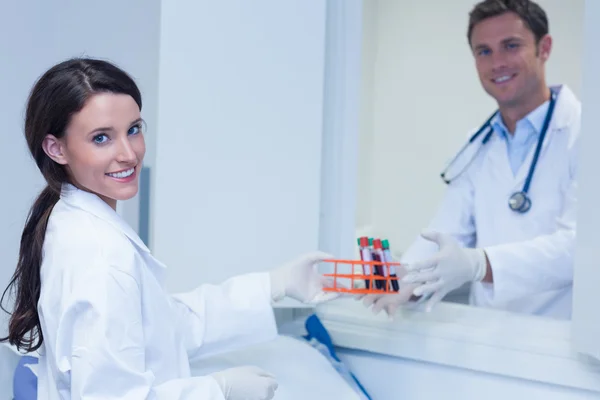 Biologi sorridenti con campione di sangue guardando la fotocamera — Foto Stock