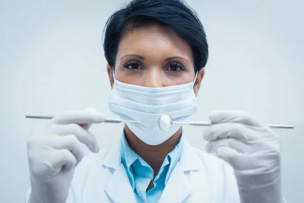 Dentista femenina en máscara quirúrgica sosteniendo herramientas dentales —  Fotos de Stock