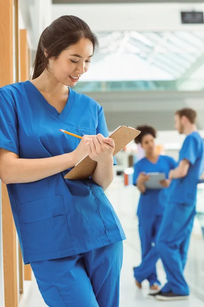 Medical student taking notes in hallway — Stock Photo, Image