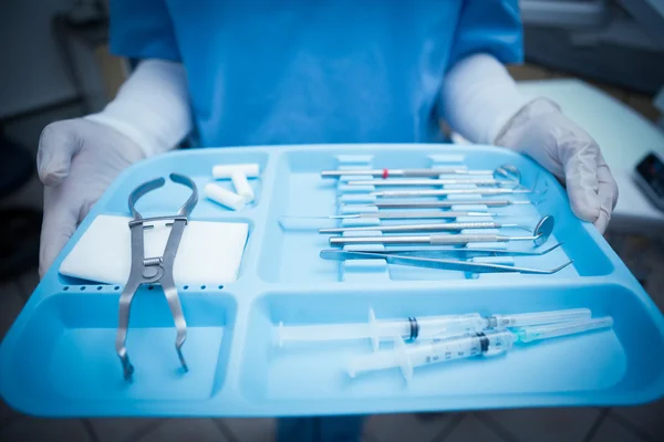 Mid section of dentist in blue scrubs holding tray of tools — Stock Photo, Image