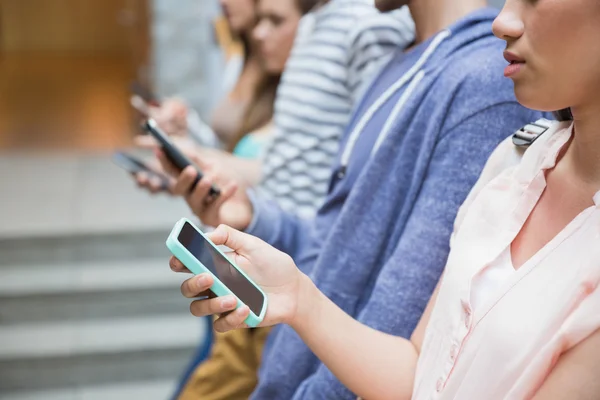 Studenten met behulp van hun smartphones in een rij — Stockfoto