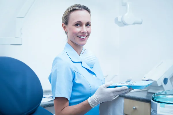 Dentista feminino em esfoliação azul segurando bandeja de ferramentas — Fotografia de Stock