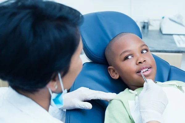 Dentist examining boys teeth in dentists chair — Stock Photo, Image