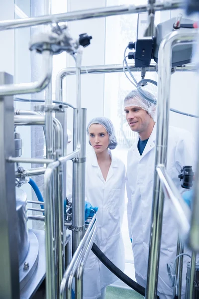 Smiling scientist with colleague looking metal gauge — Stock Photo, Image