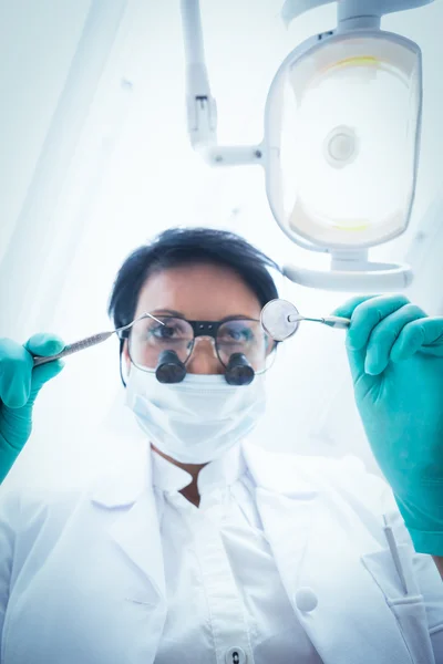 Dentista feminina em máscara cirúrgica segurando ferramentas dentárias — Fotografia de Stock